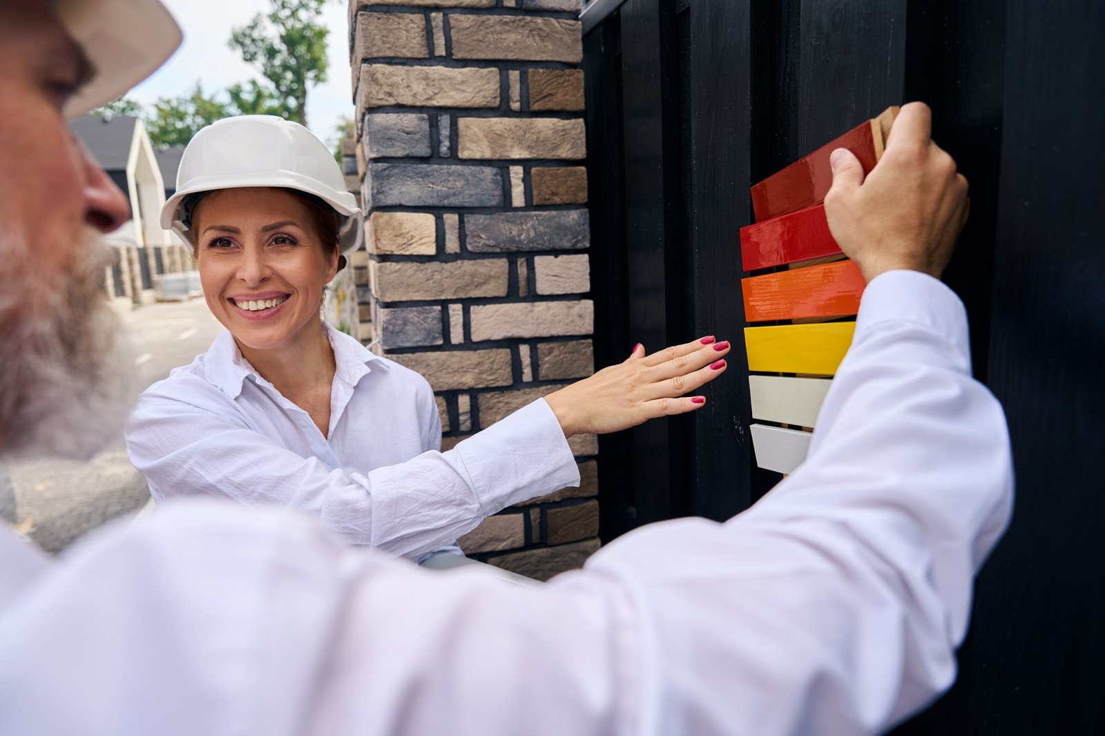 Houseowner choosing exterior paint color assisted by professional