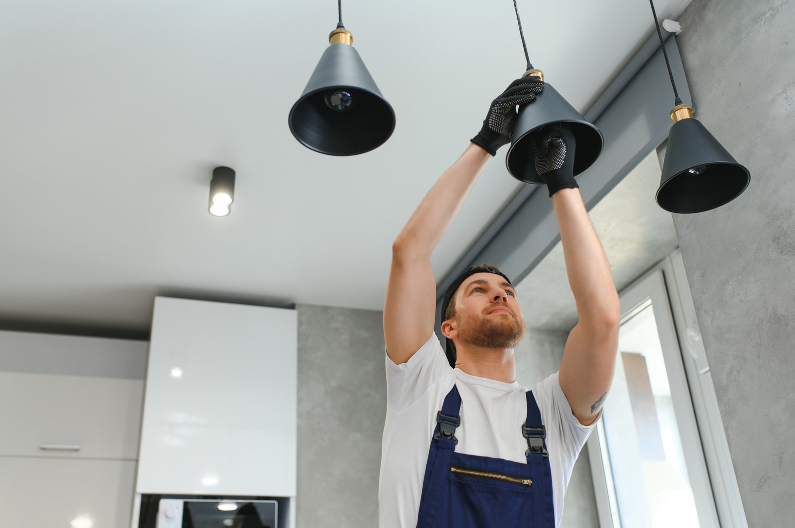 A male electrician changes the light bulbs in the ceiling light. men's household duties.