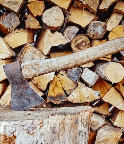 Close up of axe agains firewood background