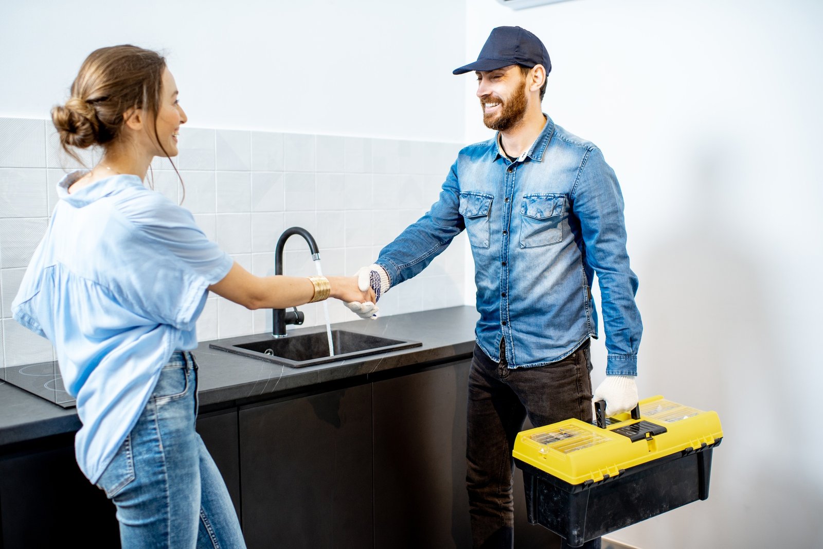 Handy man with woman in the kitchen fixing faucet