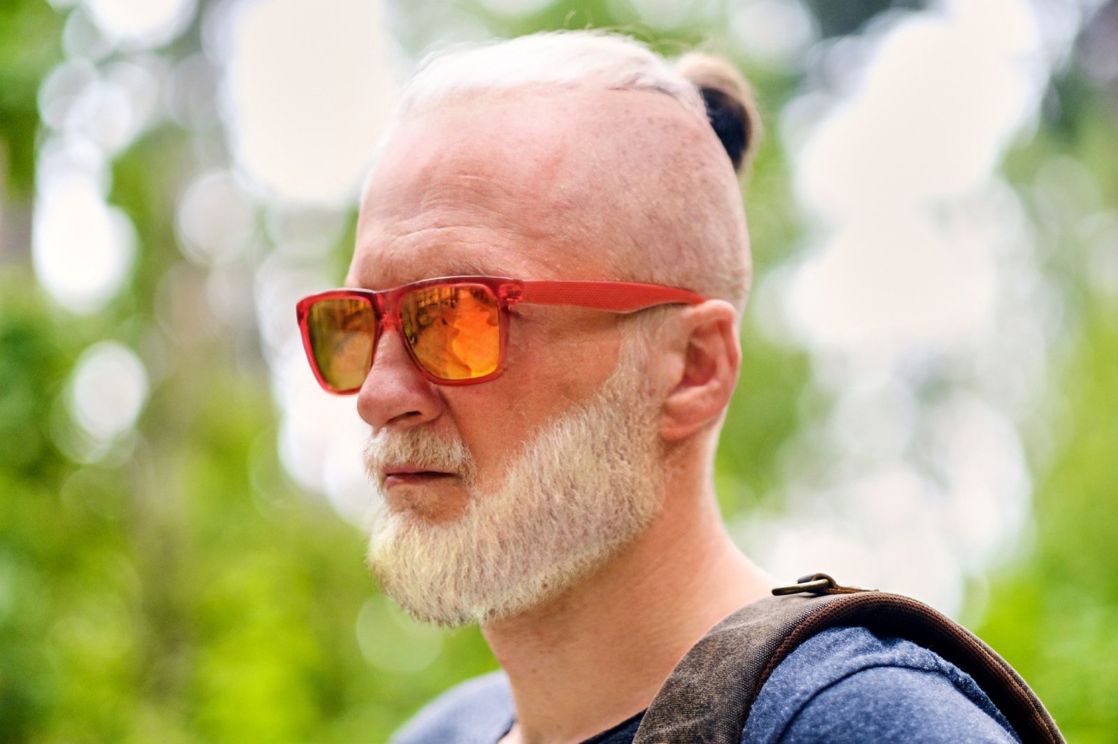 Headshot of old man with backpack walking outdoors