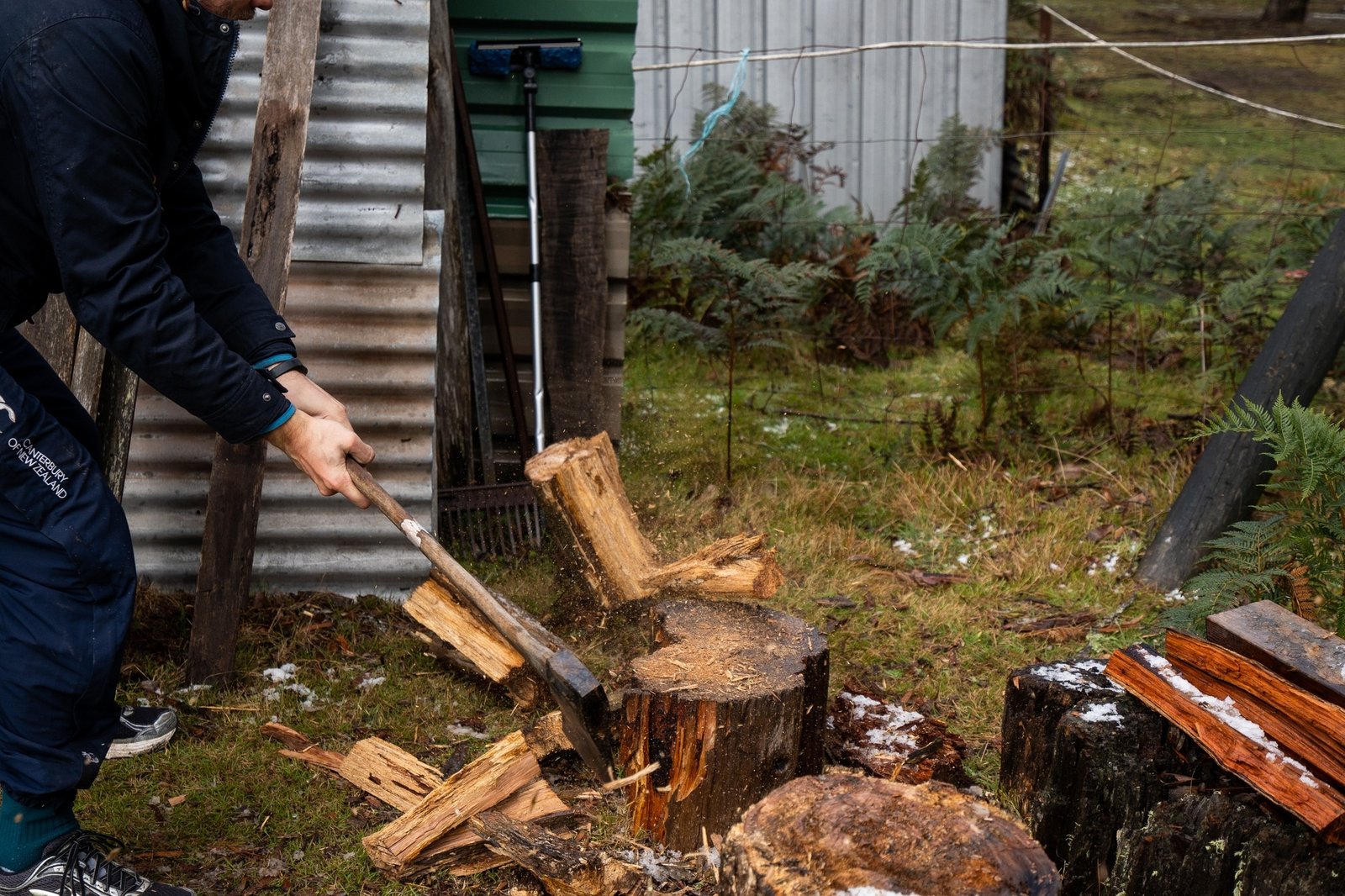 man chopping wood with axe in the snow, splitting wood for the fireplace